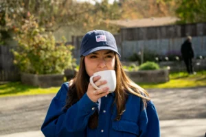 Woman Drinking Coffee Wearing Custom Richardson Hat With Woven Label Decoration
