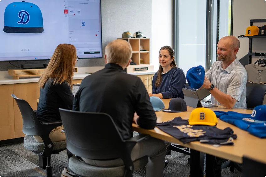 Richardson team members reviewing custom caps and uniforms during a product planning meeting.