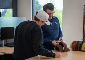Team members reviewing headwear samples during product development.