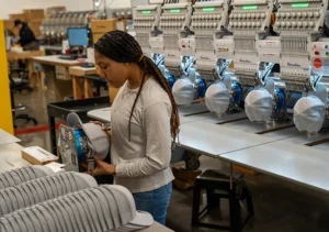 Richardson employee preparing caps for custom embroidery in the production area.