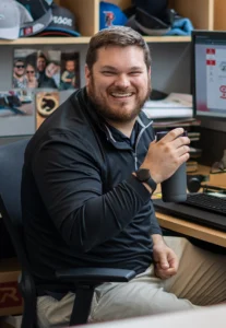 Richardson employee smiling at his desk in an office workspace.