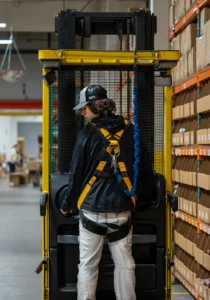 Warehouse employee operating a forklift near rows of inventory boxes.